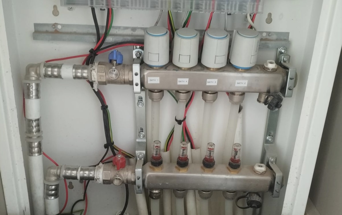 Brass manifold with thermal actuators, flow meters and zone valves for a multi-zone hydronic underfloor heating system installed by Synergy in South Africa