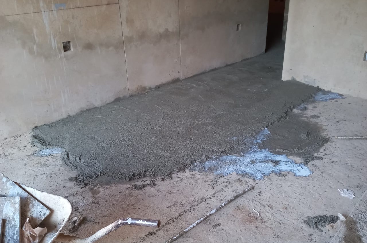 SUNPERL perlite-cement mix being laid and bonded onto a concrete slab in a South African home